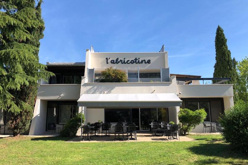 Le jardin, la terrasse et le Logis Hôtel l’Abricotine sous un ciel bleu