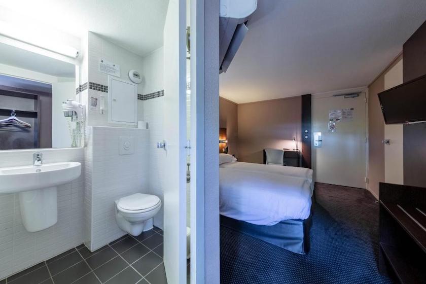 At Noemys Valence Nord, a twin room with a glimpse of the bathroom in the foreground.