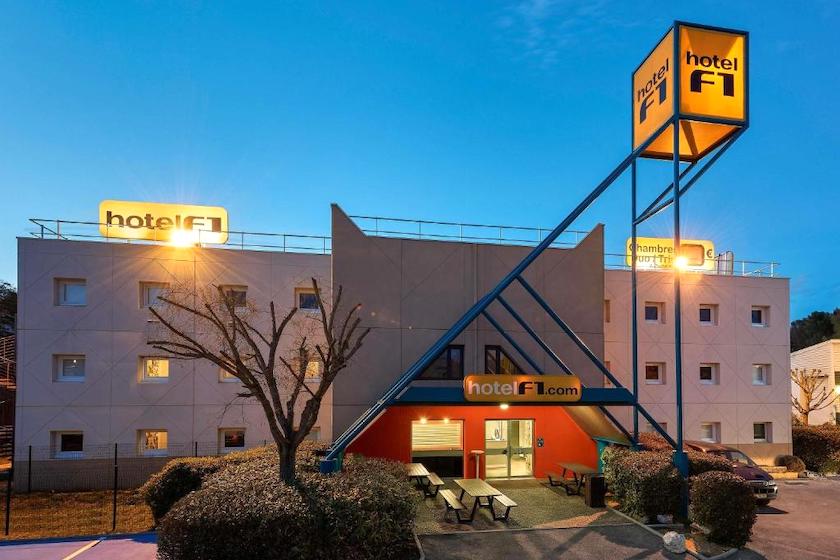 L’HotelF1 au crépuscule, avec ses enseignes illumintées visibles de l’autoroute